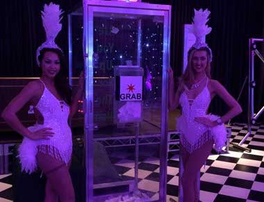 Showgirls standing by a cash cube