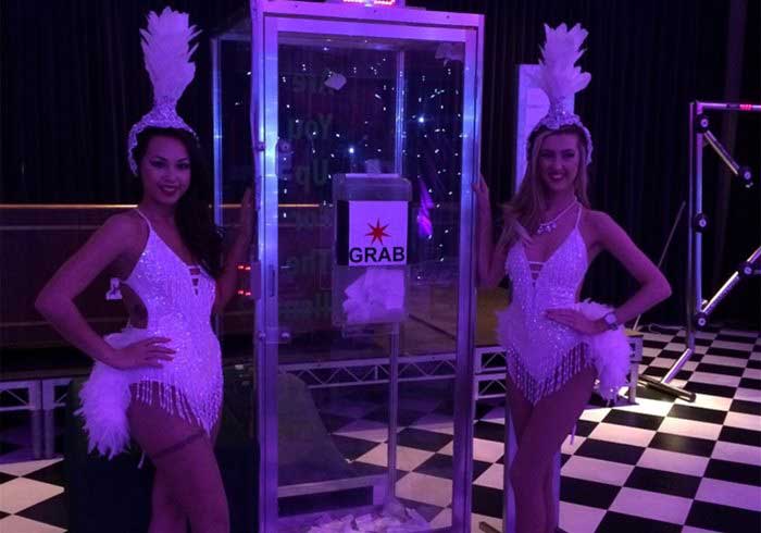 Showgirls standing by a cash cube